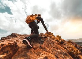 Success woman hiker hiking on sunrise mountain peak - Young woman with backpack rise to the mountain top. Discovery Travel Destination Concept